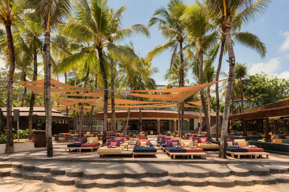 Alunê beach club at W Bali – Seminyak, with daybeds under palm trees and shade sails